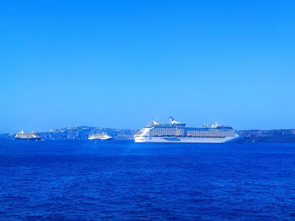 Grandi navi da crociera Royal Caribbean navigano in acque blu, con isole sullo sfondo.