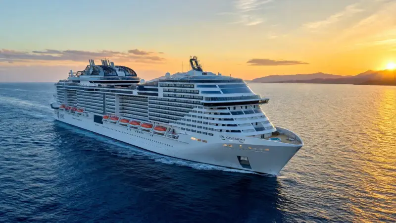 MSC Grandiosa, nave di dimensioni imponenti, solca il mare al tramonto, illuminata dalla luce dorata.